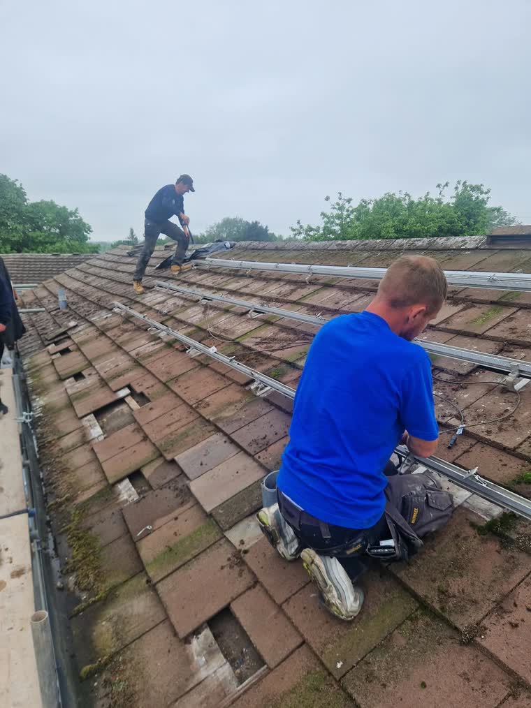 Roofers stripping the old tiles from a roof before it is re-covered