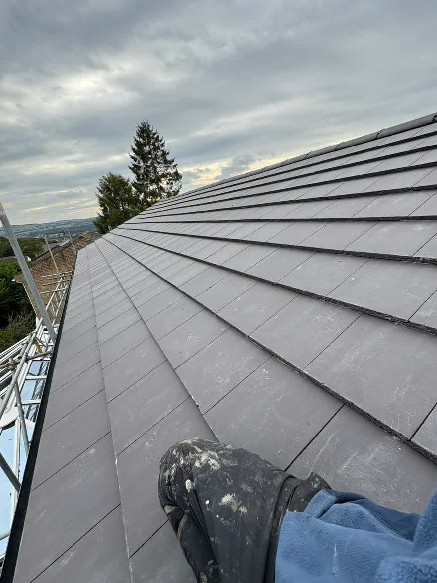Newly tiled hip roof with a bedded ridge and a chimney stack behind