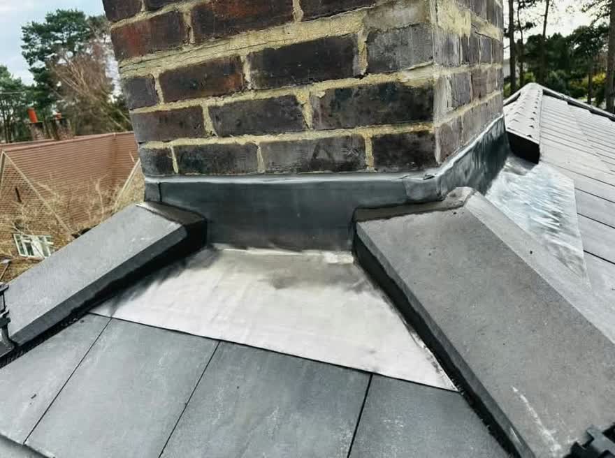 Lead tray and flashing formed around a stone chimney above a flat roof
