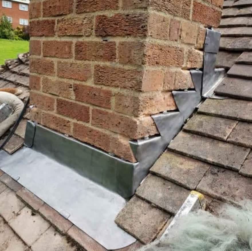 Lead flashing and soakers stepped into the side of a brick chimney