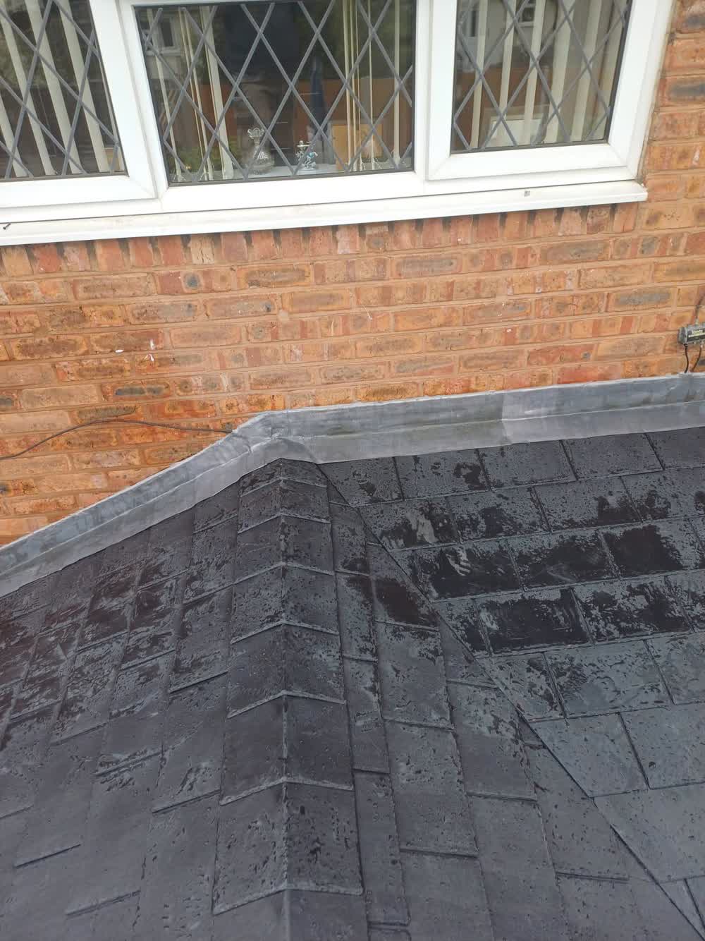 Newly laid flat roof meeting the brickwork below leaded windows