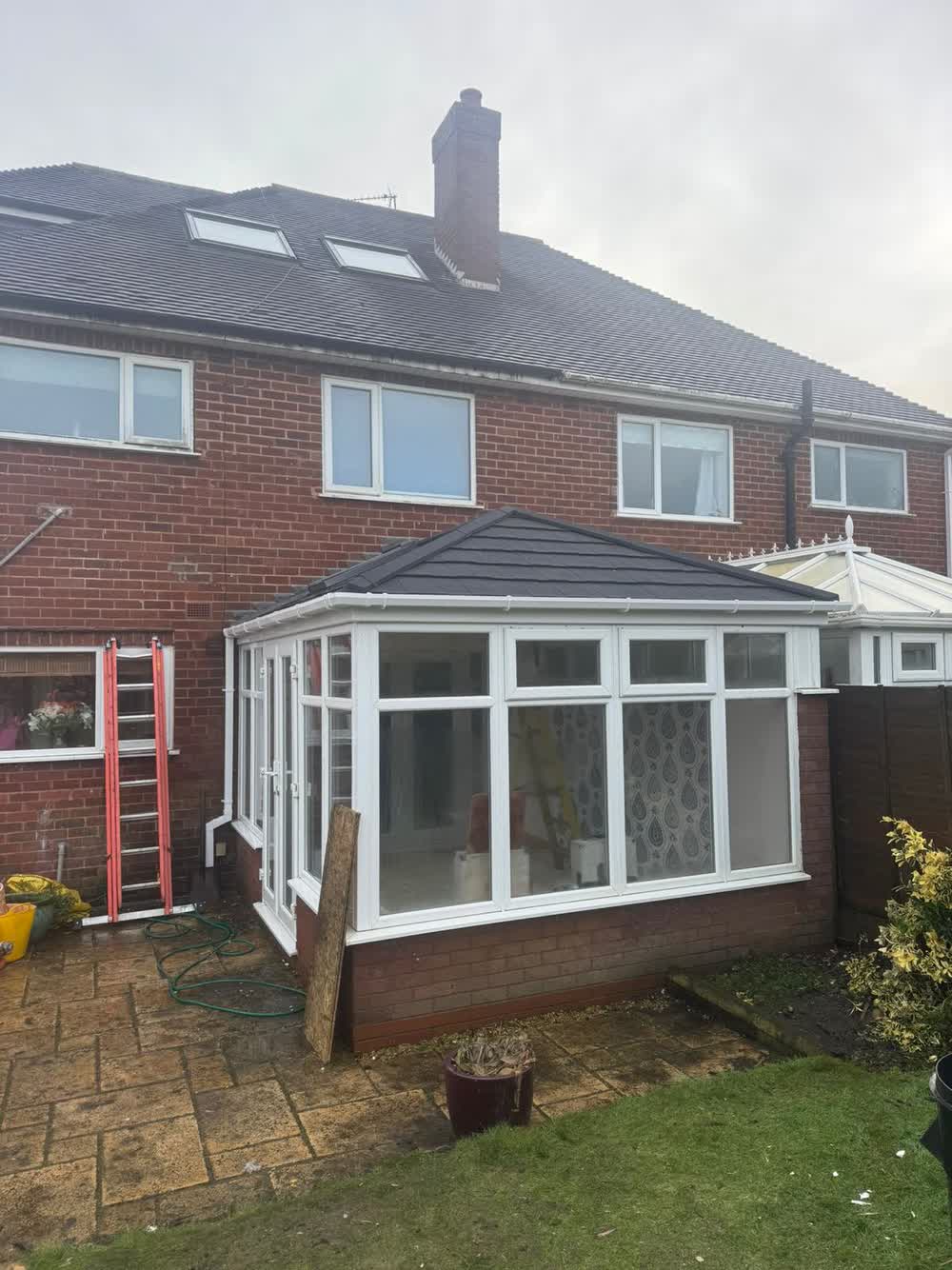Rear of a house with a white framed conservatory and a new roof